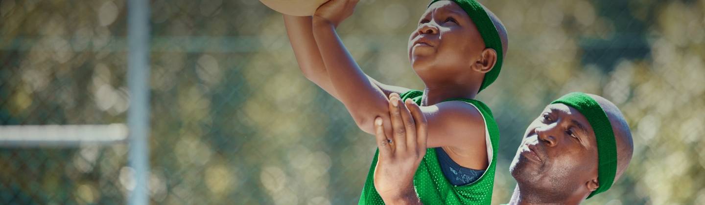 A father helps his son throw a ball