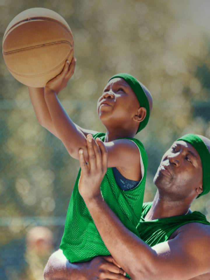 A father helps his son throw a ball